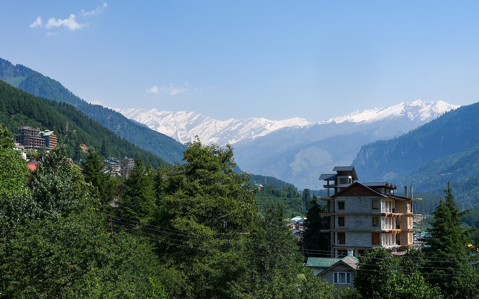 Snow-dusted peaks and pine forest above Manali town in winter